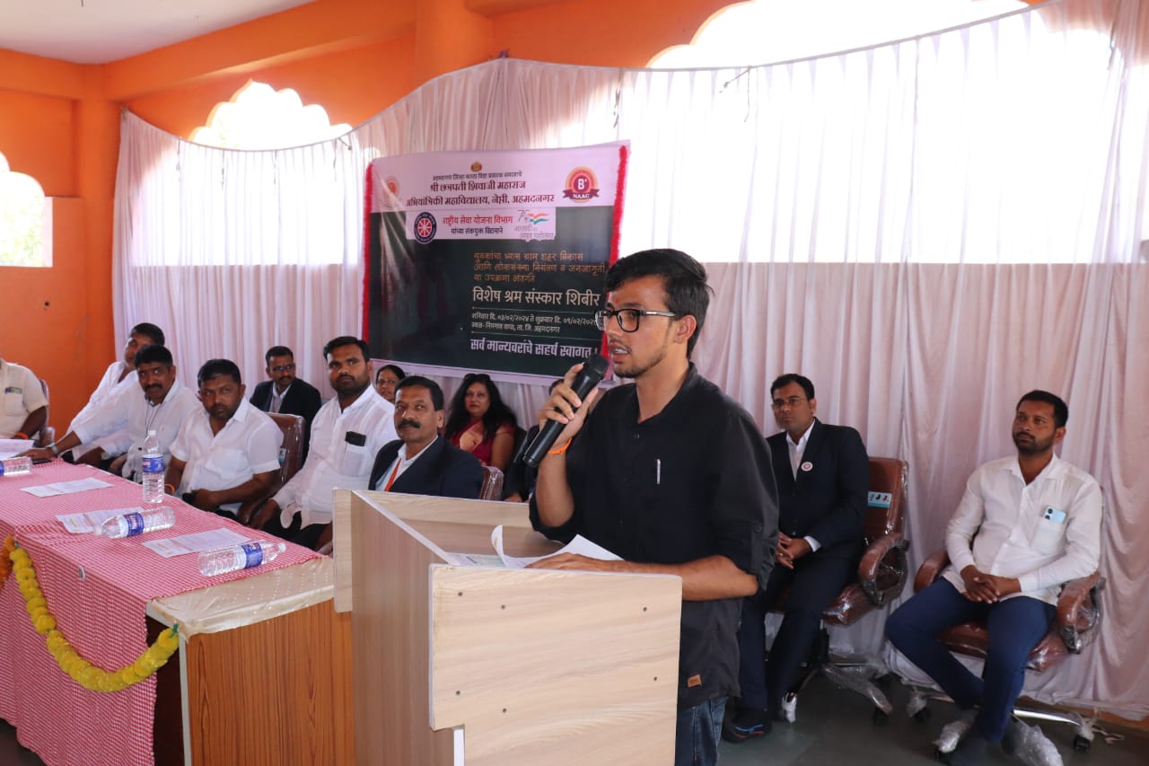 Onkar Kandekar speaking at a podium during the NSS special camp in front of invited dignitaries